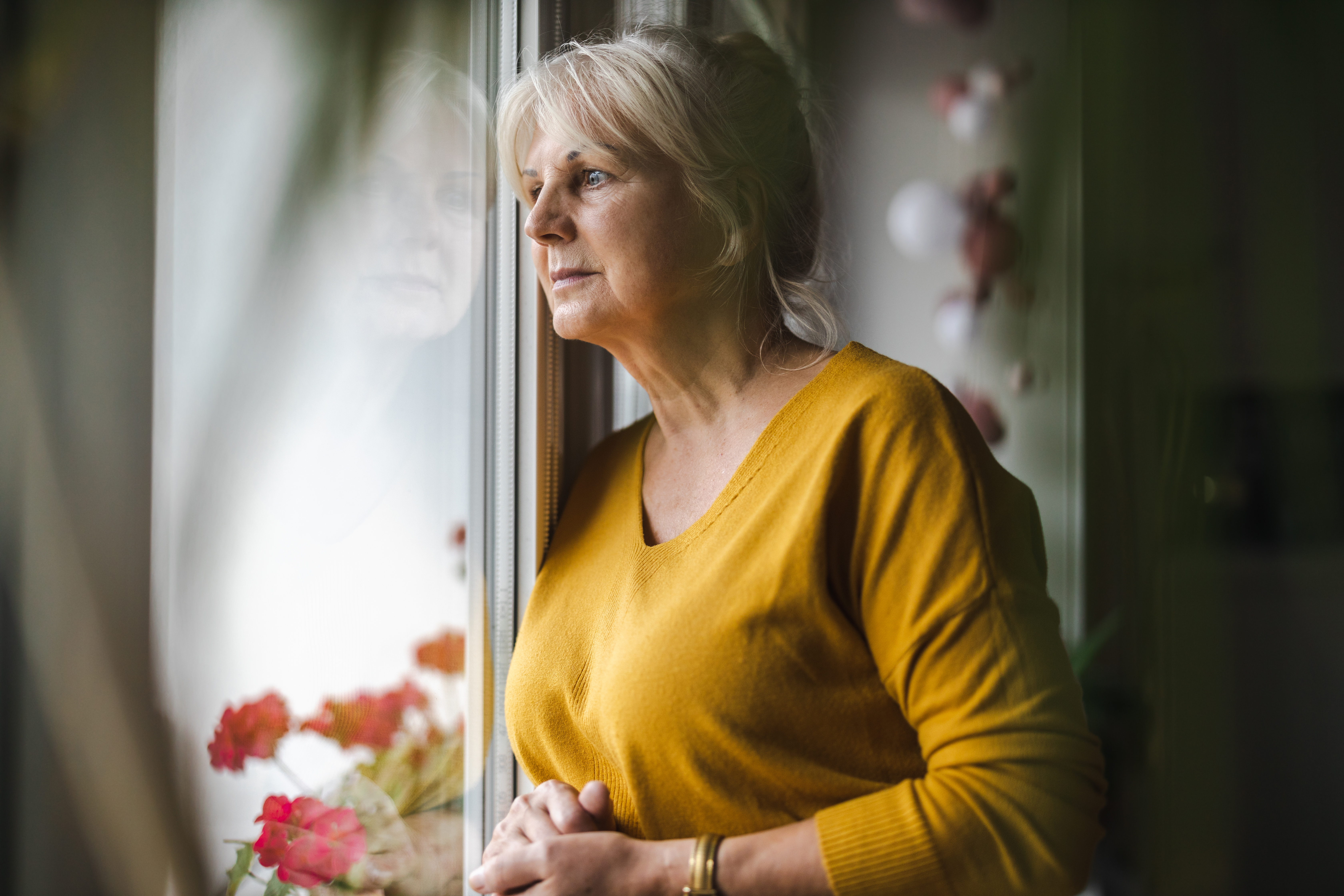 Women looking out of her window looking sad