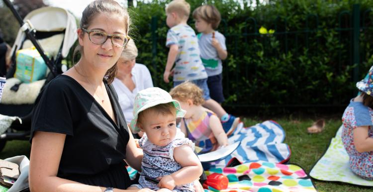 Woman sitting on a picnic blanket with her baby