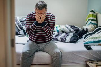 Man sitting on bed with head in his hands