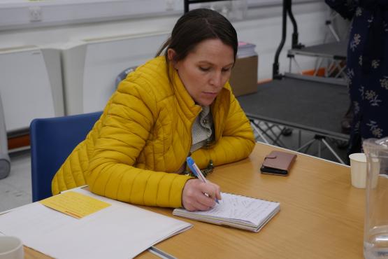 Lady sitting down at a table and making notes